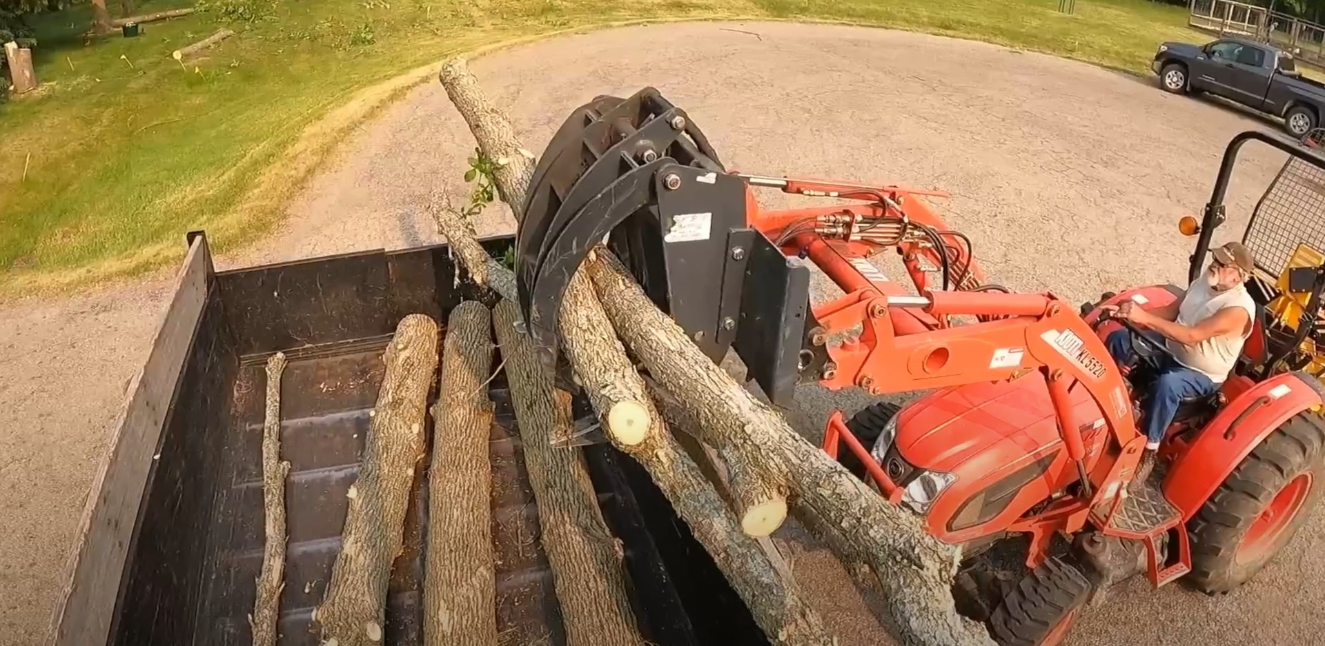 Orange tractor loading cut tree logs for efficient debris removal