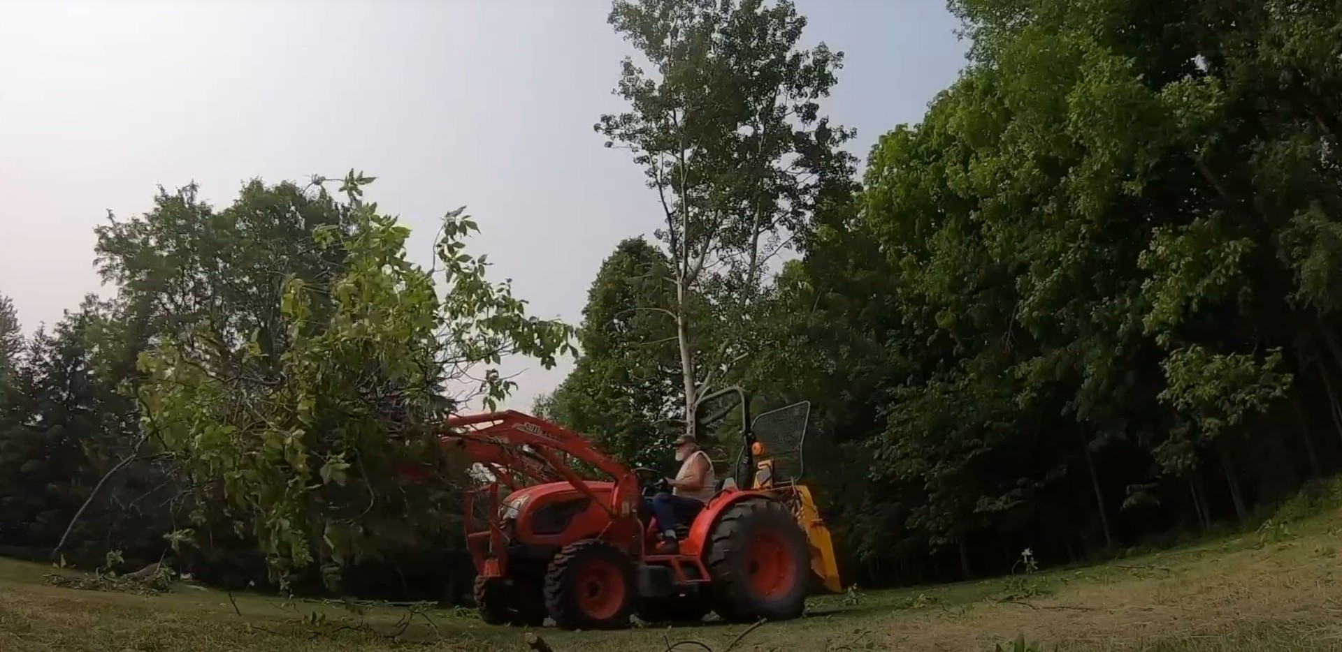 Red tractor with wood chipper clearing trees and debris in residential area